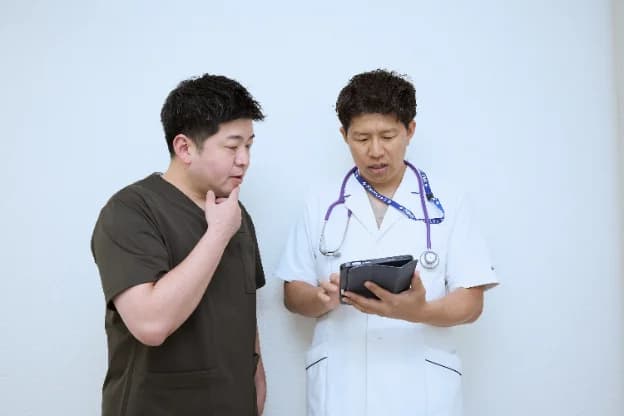 タブレットを囲んで相談する歯科医師と医師