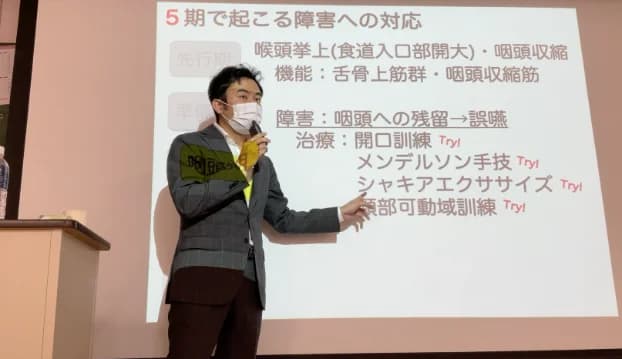 摂食嚥下のスライドを使って講義する歯科医師